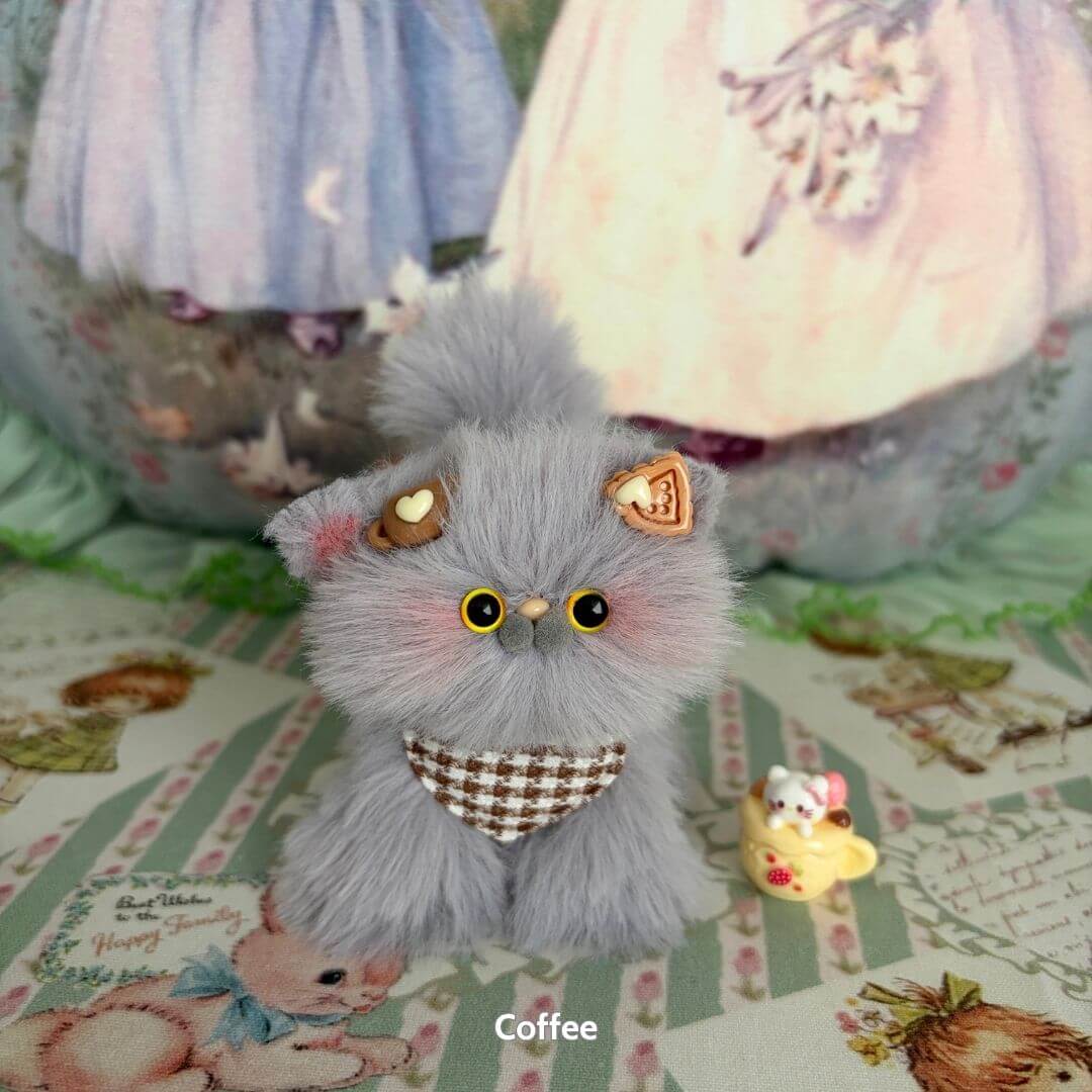 Adorable handmade kitten from the Grey Kitten Collection, fluffy grey fur, wearing a checkered scarf, accompanied by a tiny yellow cup.