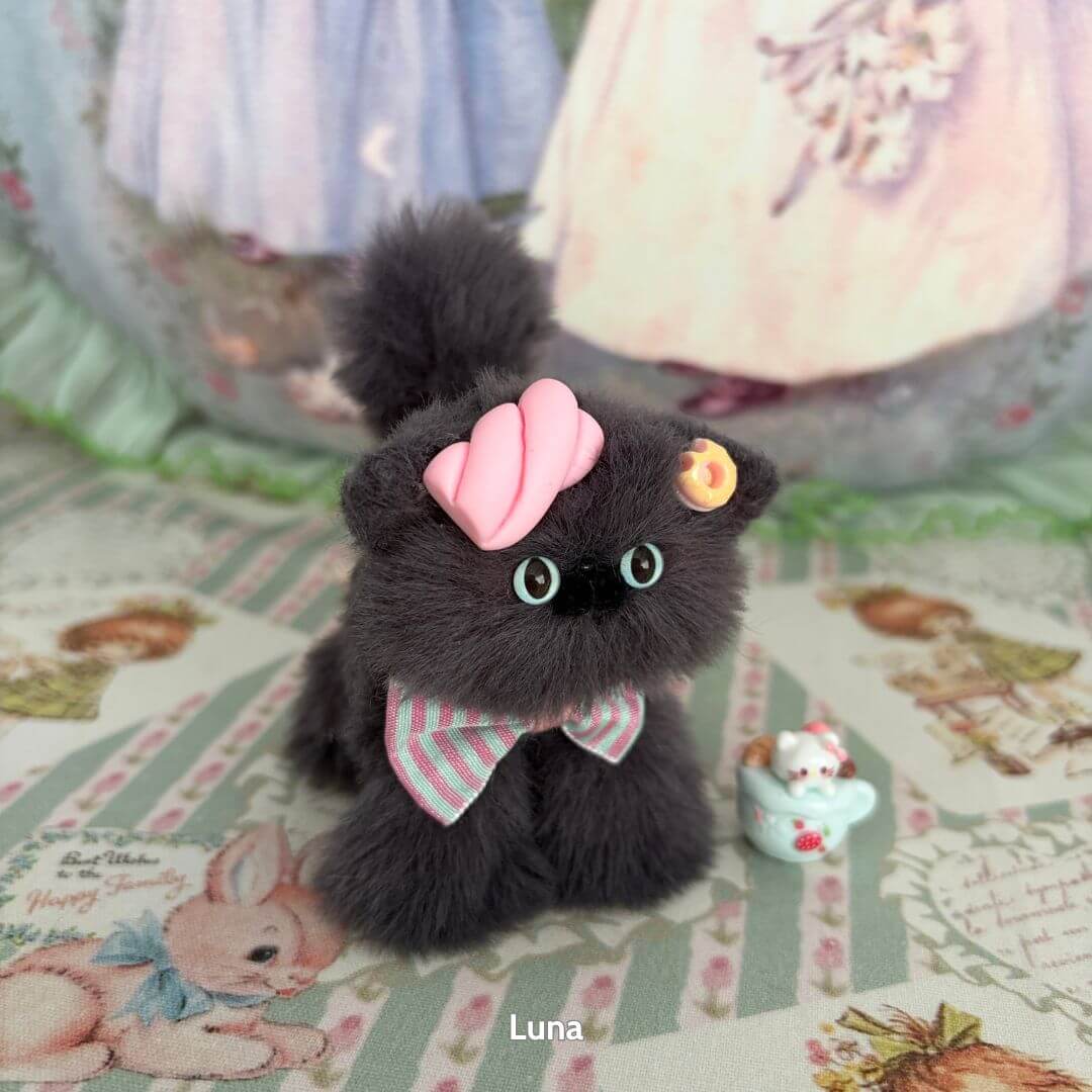 Fluffy black kitten figurine from the Grey Kitten Collection, wearing a pink bow and decorated with a cupcake accessory.