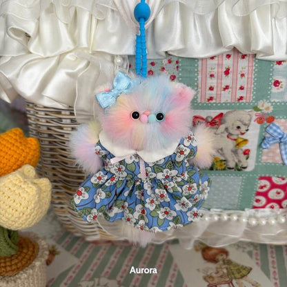 Adorable handmade kitten in a floral dress with a blue bow, part of the Pawsh Pendants collection, colorful and fluffy cat figurine.