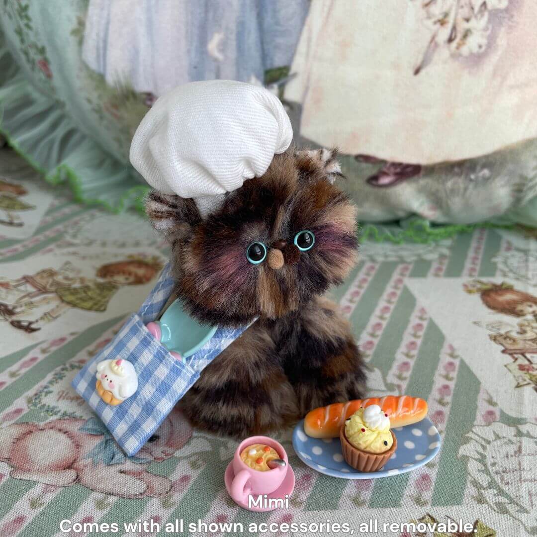 Handmade kitten in chef hat and apron, surrounded by miniature cooking tools and treats, from Purrfect Chef Kitten Sets.