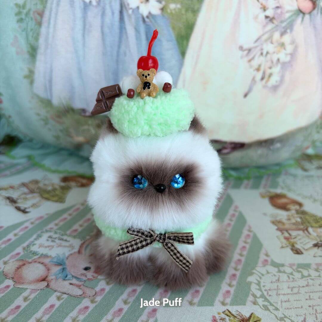 Mewlicious Collection: handmade kitten figurine with green frosting, cherry, and teddy bear decoration, fluffy cat style, cute animal collectible.