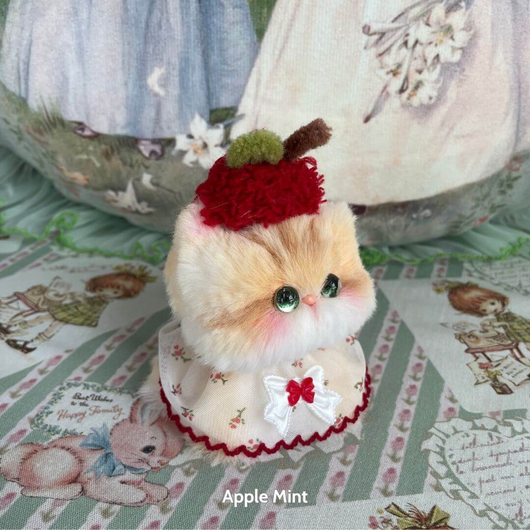Adorable handmade kitten from the Mewlicious Collection, wearing a cherry-topped hat and a frilly dress, crafted in UK.