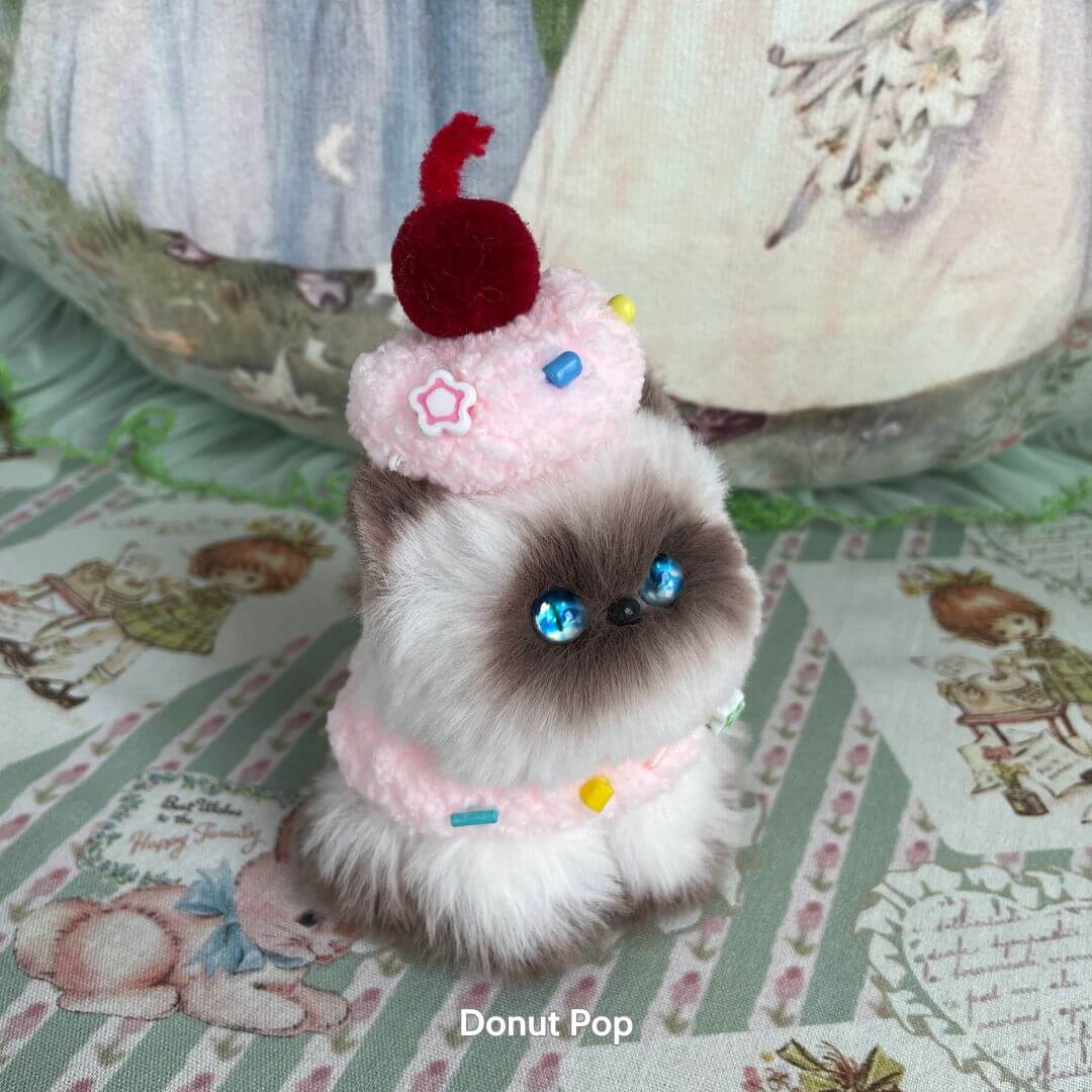 Handmade kitten from Mewlicious Collection, fluffy gray and white cat figurine styled as a frosted cupcake with a cherry on top.