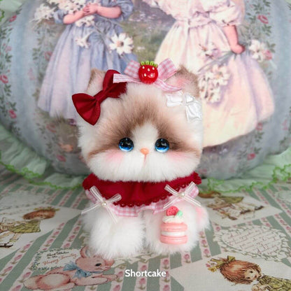 Adorable miniature kitten from the Enchanted Big Paws Collection, featuring fluffy fur, stylish ribbon, and cute dessert accessory.