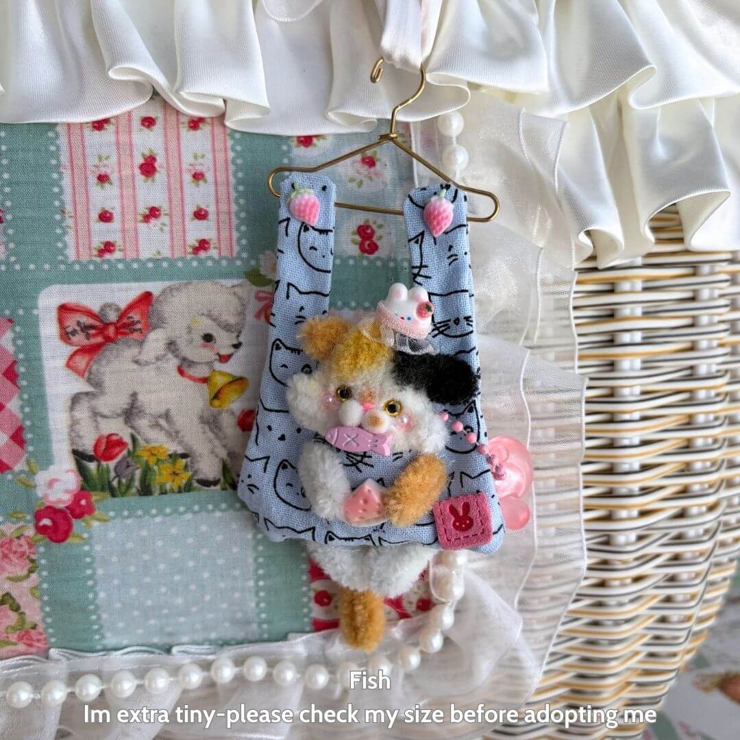 Cute handmade kitten hanging from a mini hanger, fluffy cat figurine in pastel colors, part of Little Hanger Pals collection.