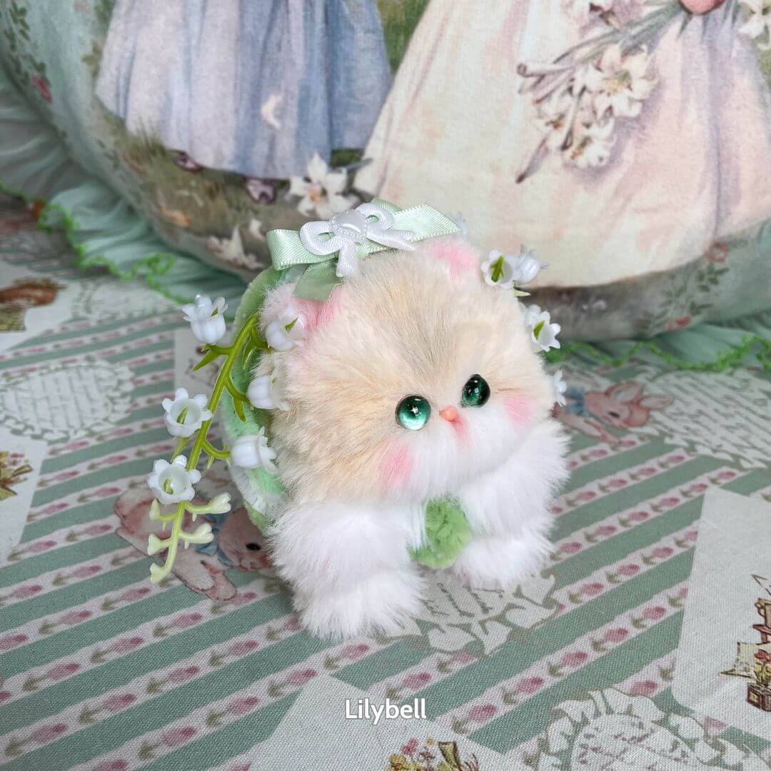 Alt Tag: Handmade kitten from the Blossom Kitten Collection, fluffy white and cream, adorned with green bow and flowers.