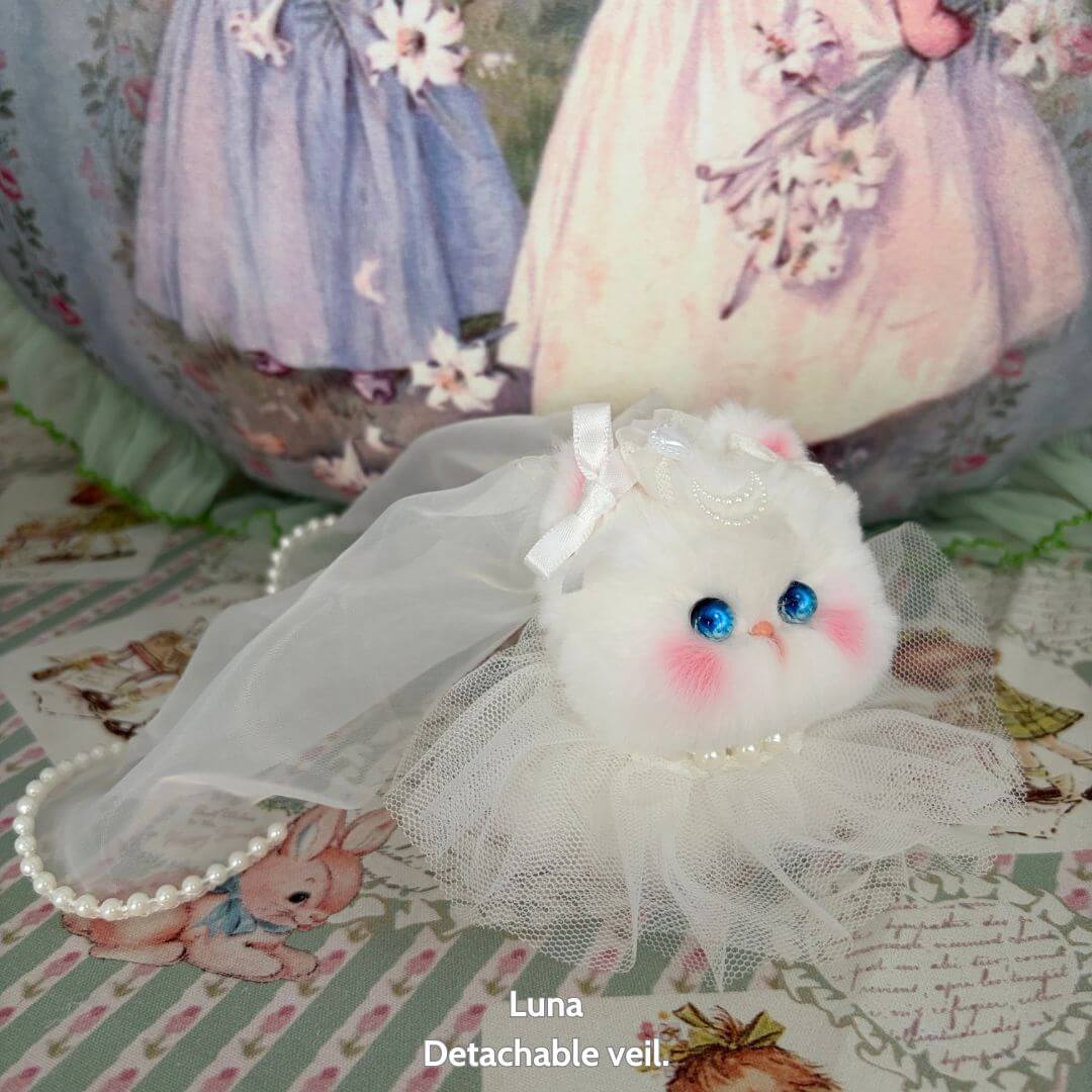 Handmade kitten from the Fairy Paws Collection, fluffy white with blue eyes, wearing a detachable veil and pearl necklace.