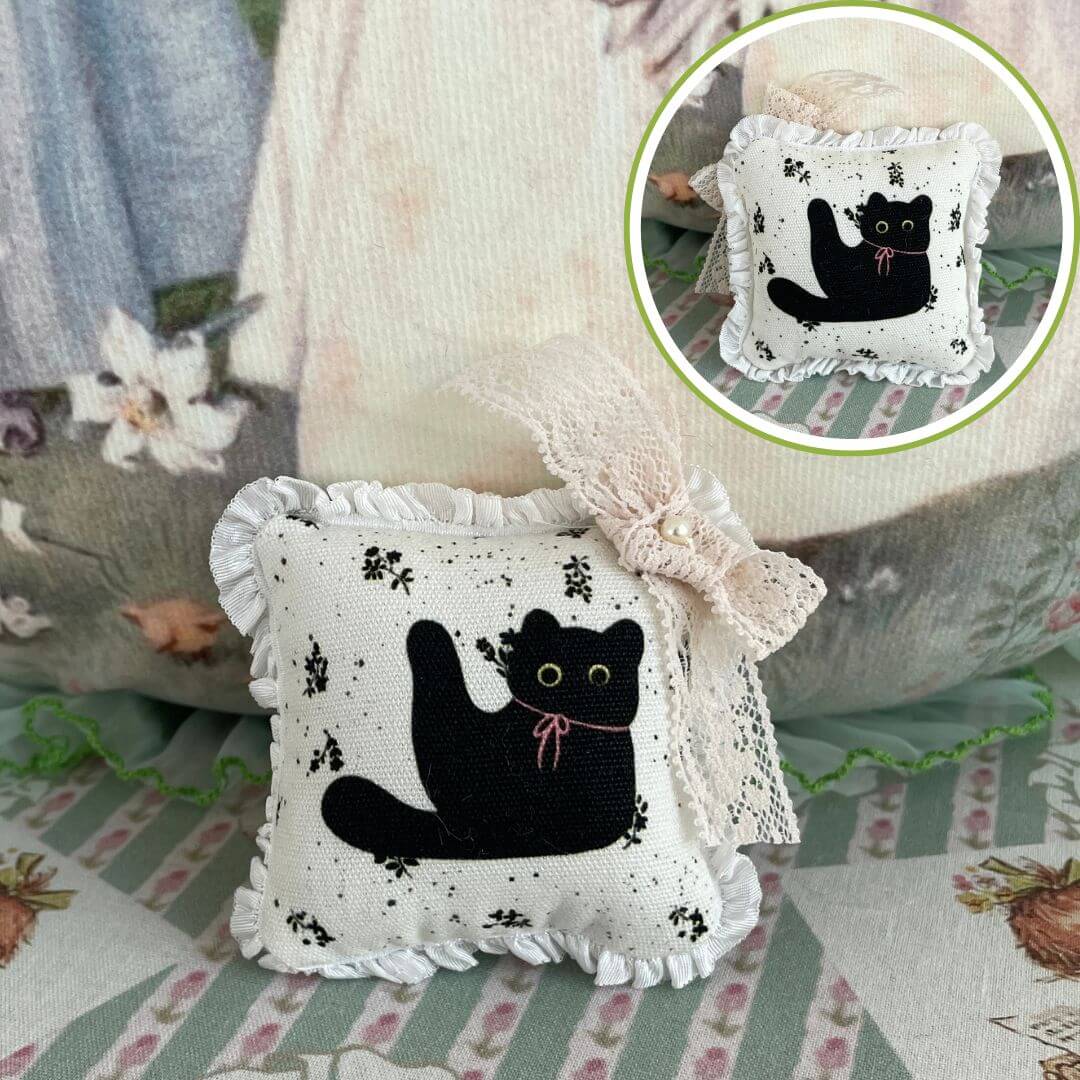 Handmade mini cuddle critter cushion featuring a black cat design with a hand-stitched bow, perfect for dolls or desktop decor.