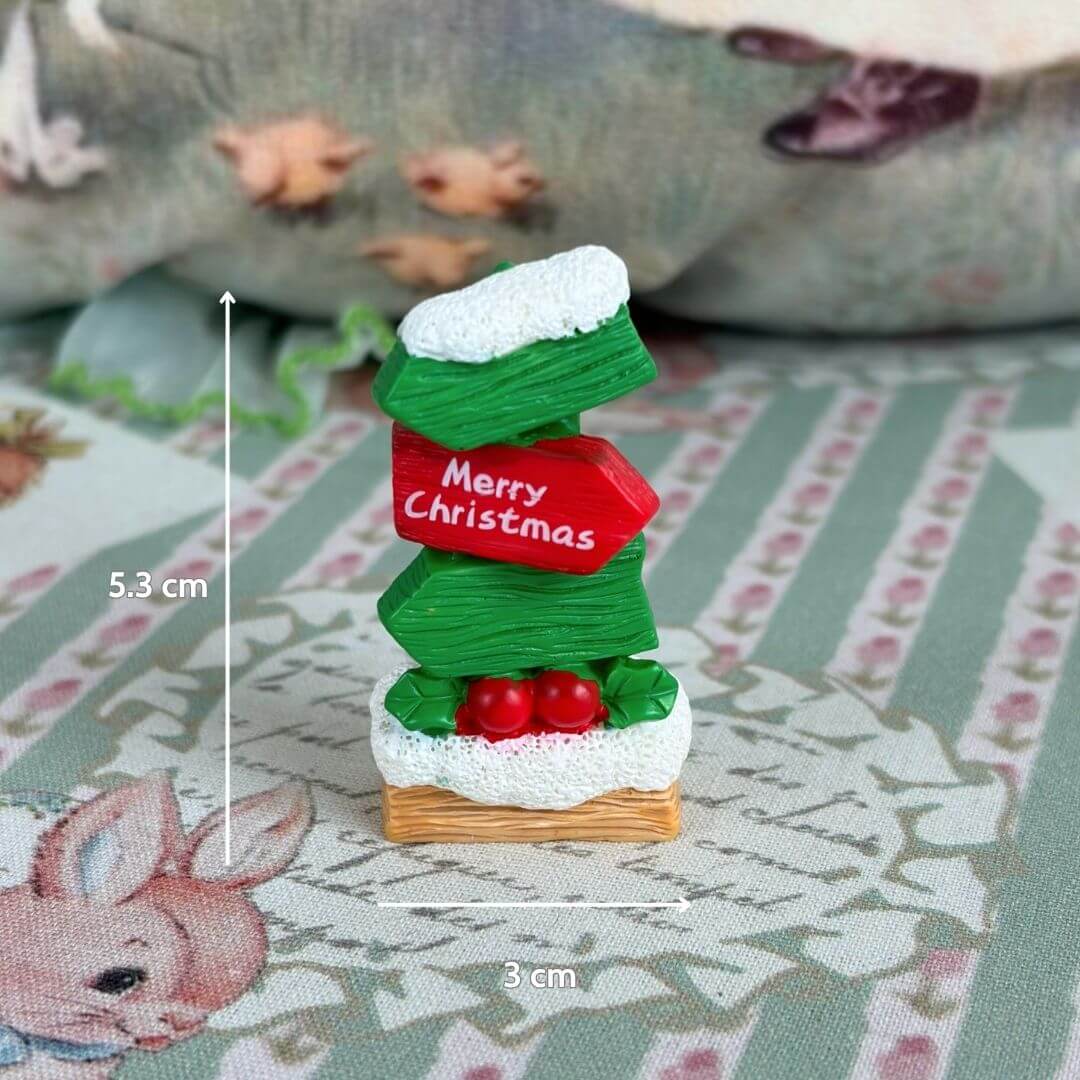 Miniature Christmas Accessories featuring a handmade sign with 'Merry Christmas', greenery, and red accents for festive dollhouse decor.