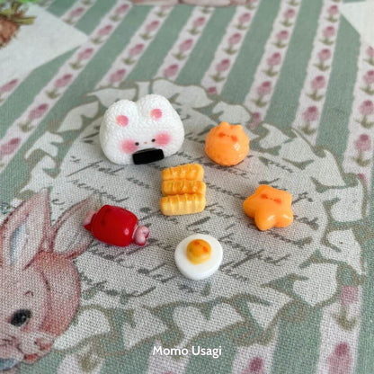 Mini Cat Bento Box featuring a cute fluffy kitten onigiri and colorful miniature food pieces on a floral patterned backdrop.