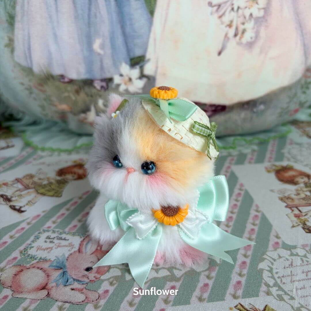 Adorable handmade kitten from the Blossom Kitten Collection, featuring a fluffy pastel coat, a mint bow, and a sunflower accessory.