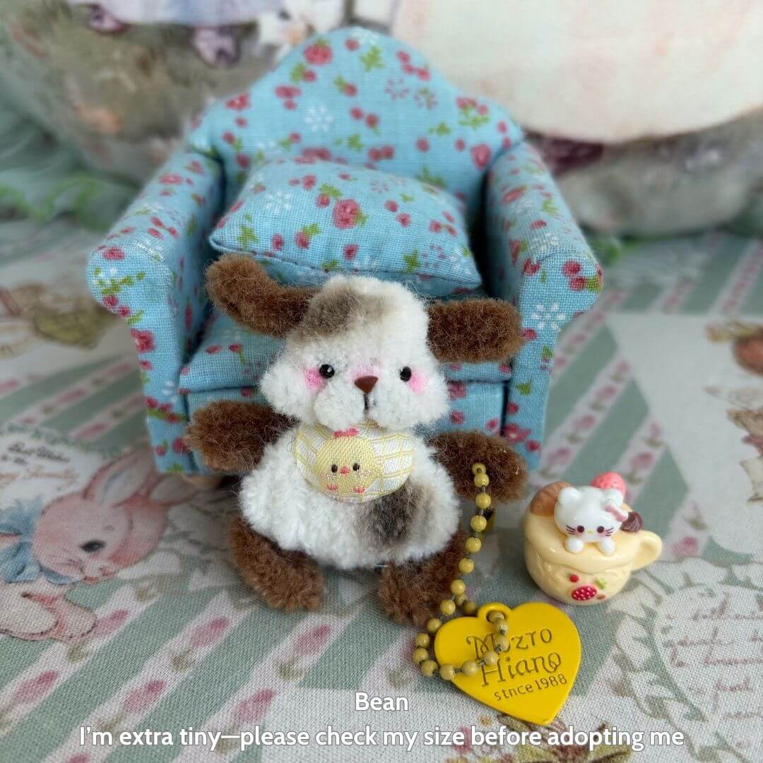 Adorable handmade miniature pipe cleaner kitten with fluffy fur, sitting in a floral chair, alongside cute animal collectibles.