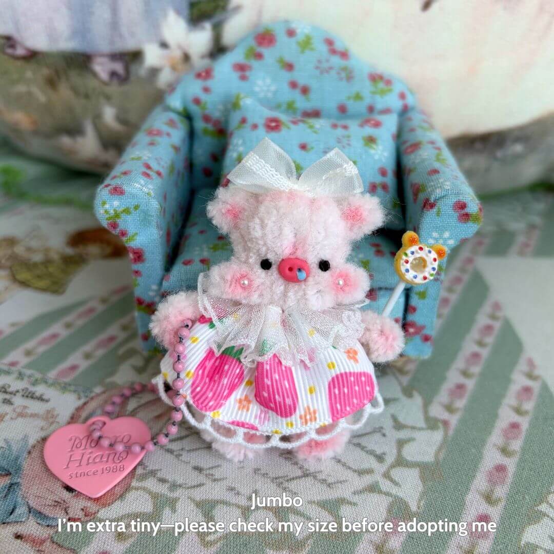 Miniature Pipe Cleaner Animals: kawaii pink pig figurine in a floral dress, holding a lollipop, sitting on a blue chair.