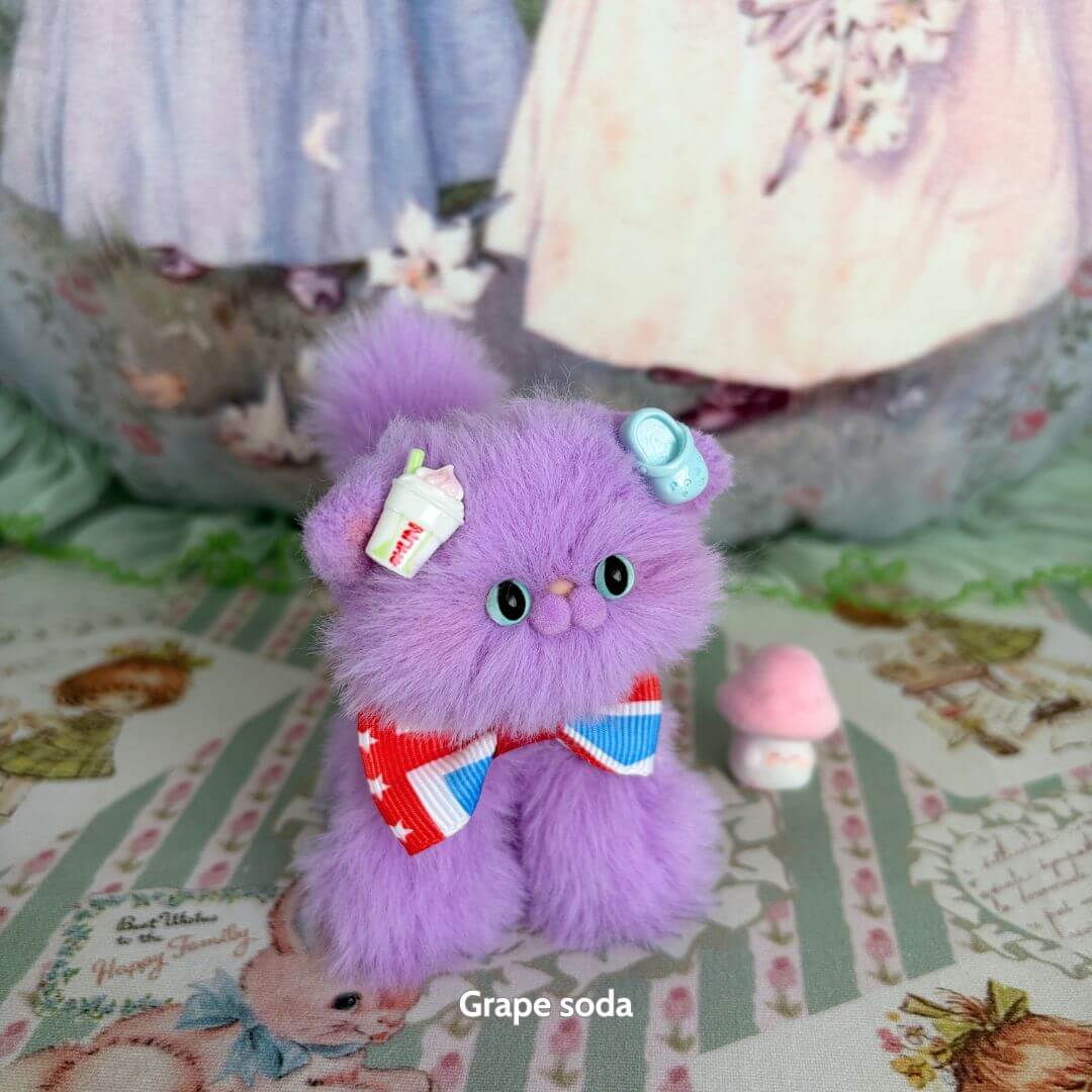 Miniature kitten from the Fruity Kitten Collection, fluffy purple cat figurine with a red and blue bow, holding grape soda accessories.