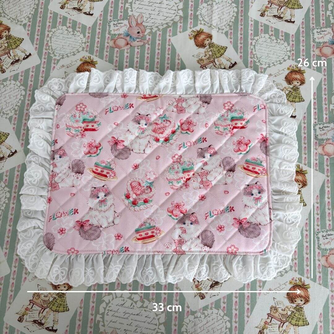 Handmade Sweet Tea Mat featuring a pink quilted surface with ruffled lace trim, charming floral patterns, and whimsical cat illustrations.
