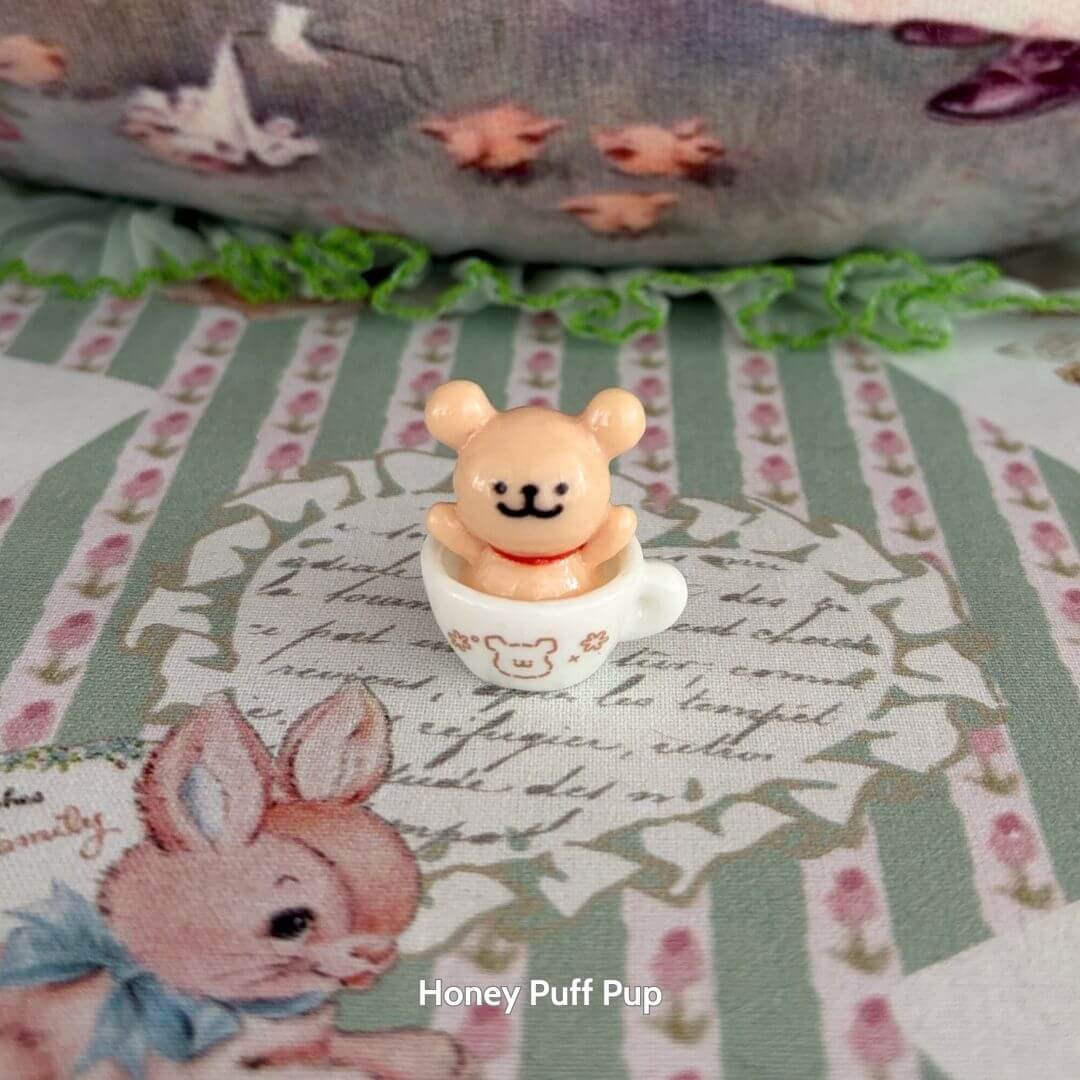 Tiny Puppy Cup featuring a cute miniature bear figurine sitting in a small cup with soft colors, ideal for collectible decor.