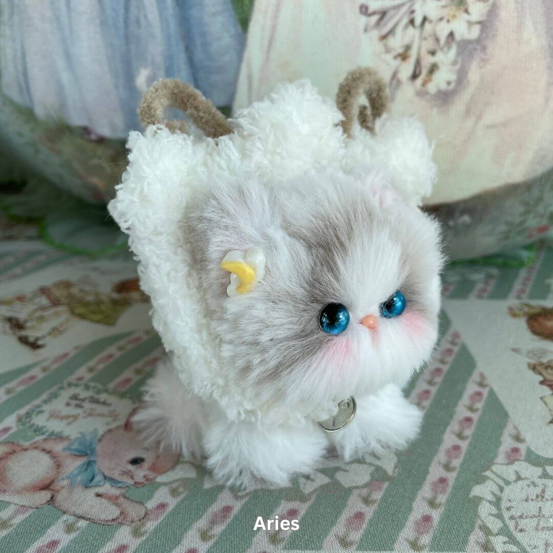 Aries-inspired plush kitten with horns, blue eyes, and faux fur from the Zodiac Kitten Collection, ideal handmade decoration or toy.