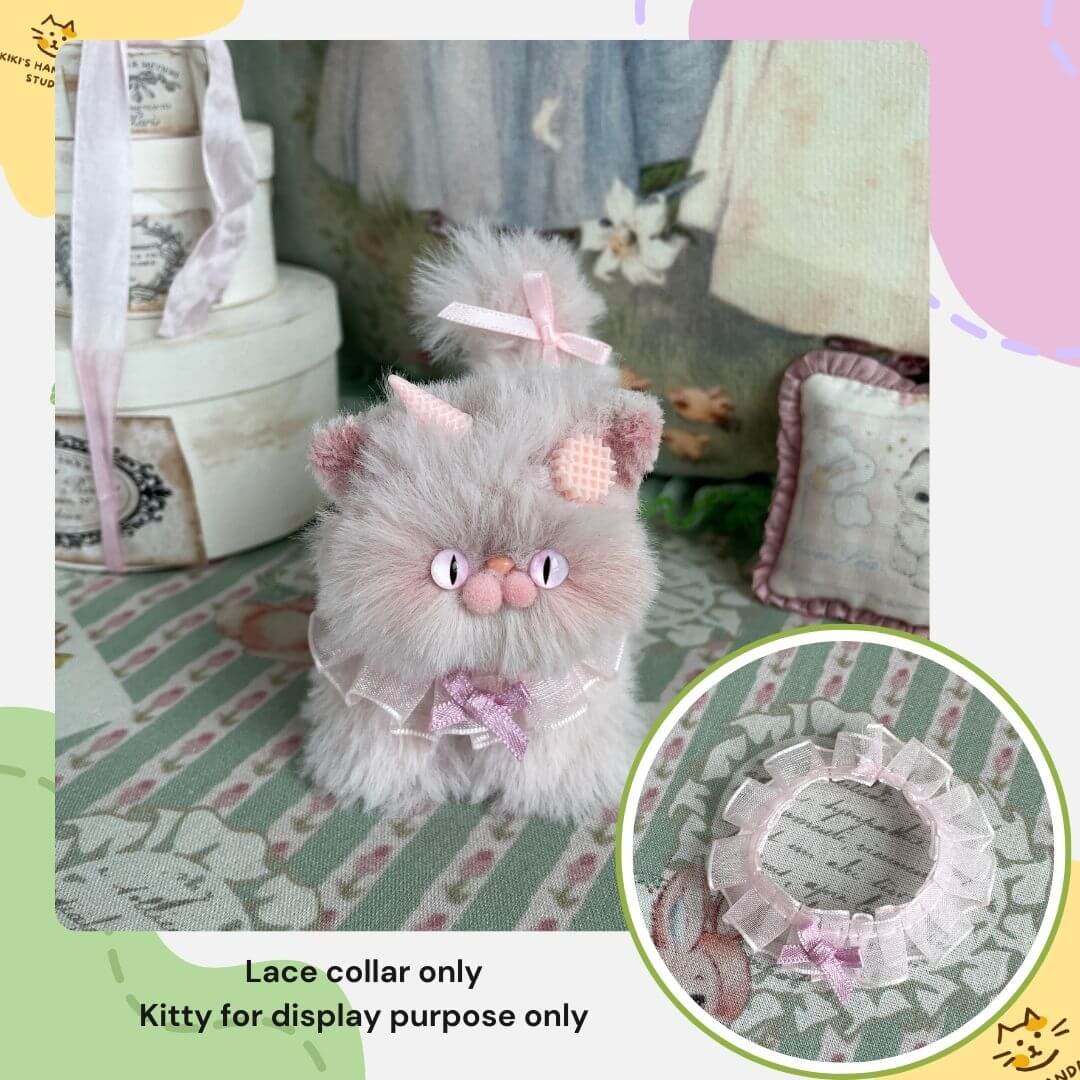Plush toy kitten wearing a handmade lace bow collar with a decorative background.