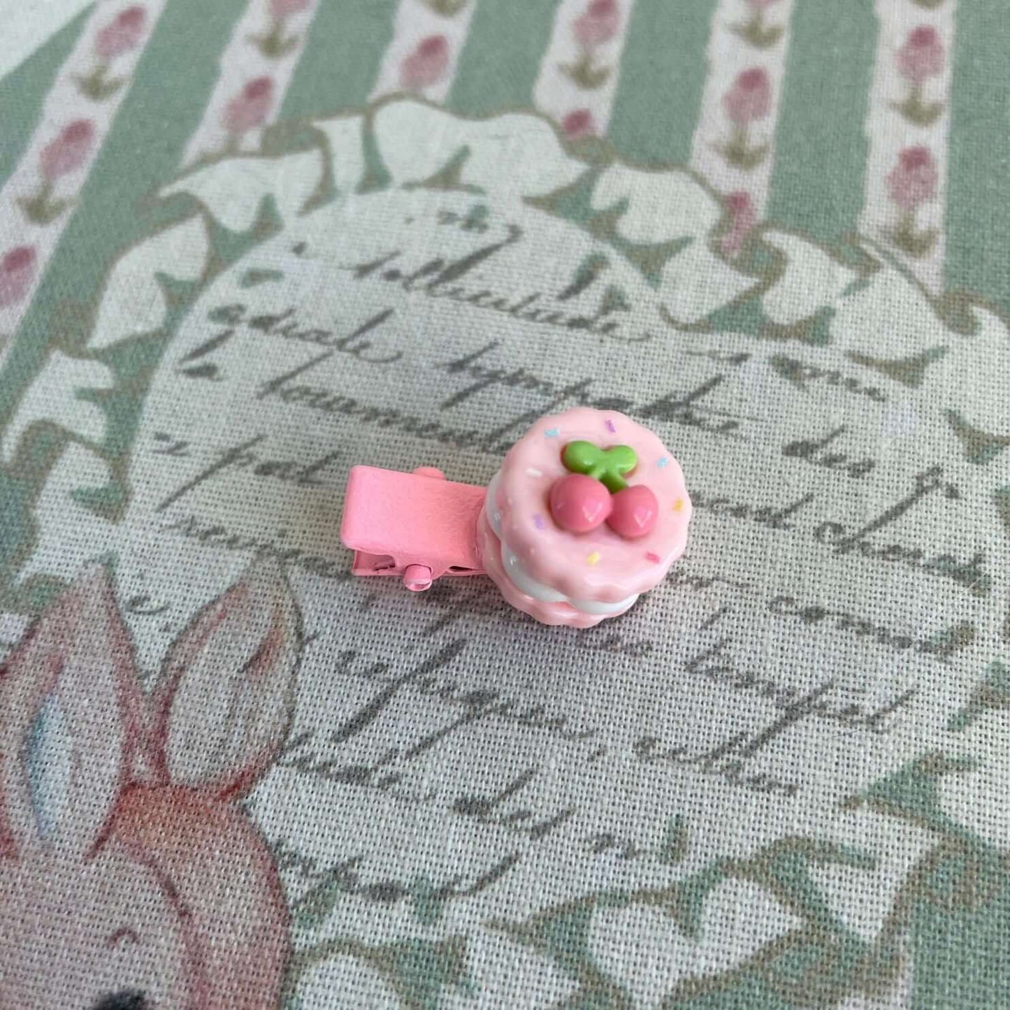 Pink handmade mini clip shaped like a cake with strawberries, perfect for decorating handmade plush toys or as an accessory for clothes.