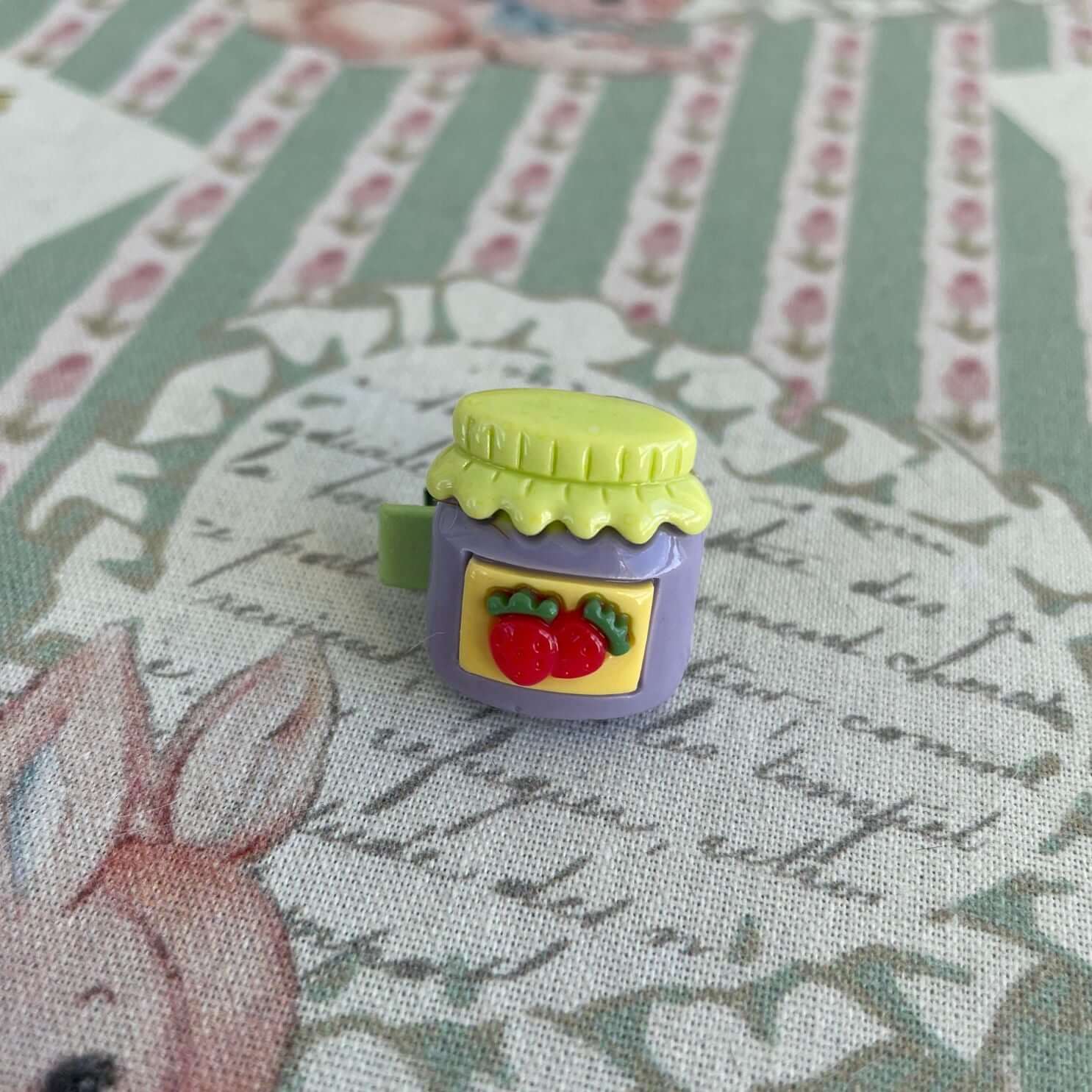 Handmade mini clip featuring a whimsical jam jar design with strawberry decoration, perfect accessory for plush toys like kittens or puppies.