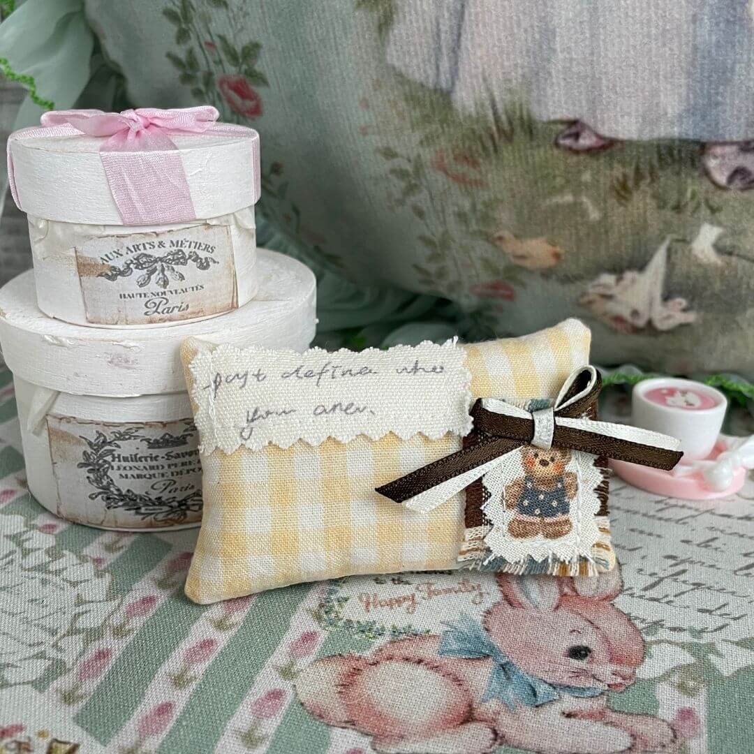 Handmade mini pillow with yellow plaid pattern and decorative bow, perfect for dollhouse or kitten accessories. Adds charm and warmth to mini settings.