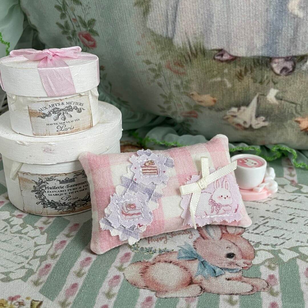 Handmade mini pillow with pink check pattern, adorned with cute fabric patches, ideal for dollhouses or miniature animal decor.