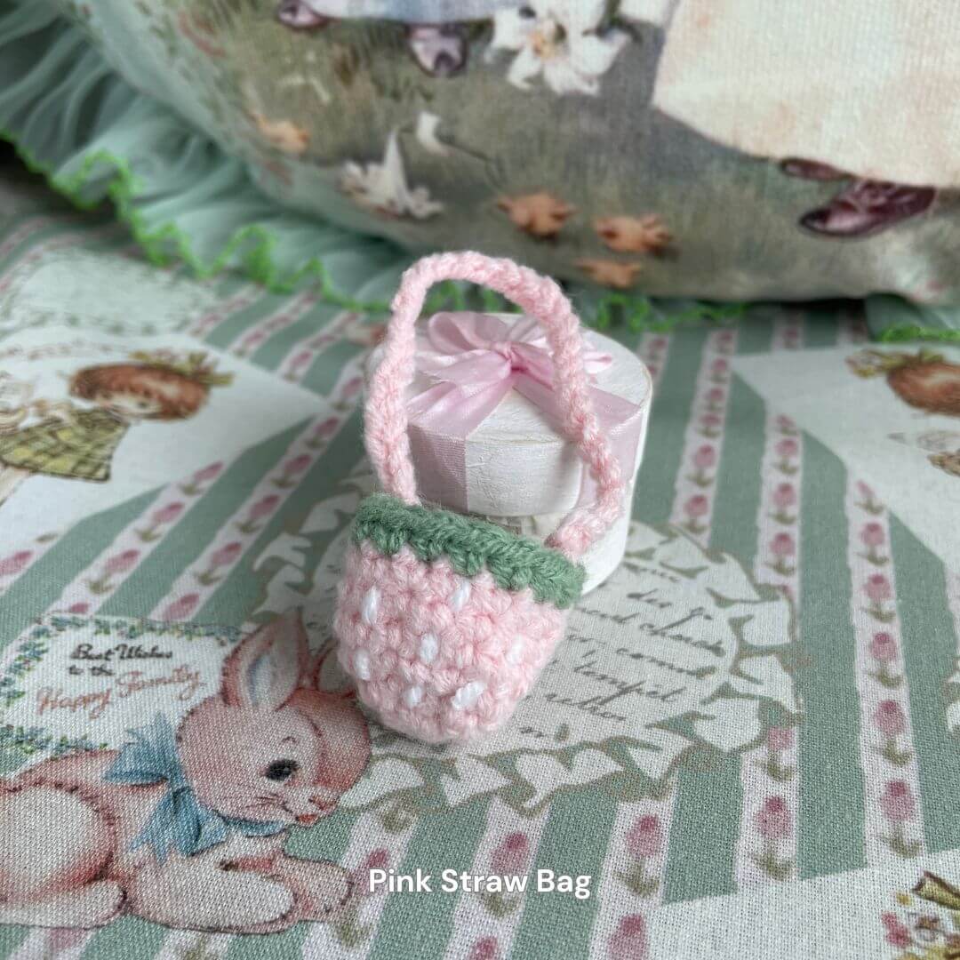 Handmade pink straw bag accessory for plush toys, surrounded by cute animal-themed decor. Perfect for styling plush kittens and puppies.