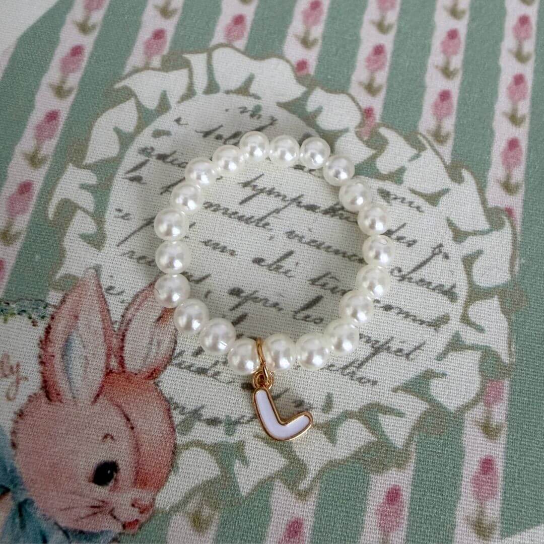Initial Pearl Necklace featuring faux pearls and a delicate letter charm on a patterned fabric background.