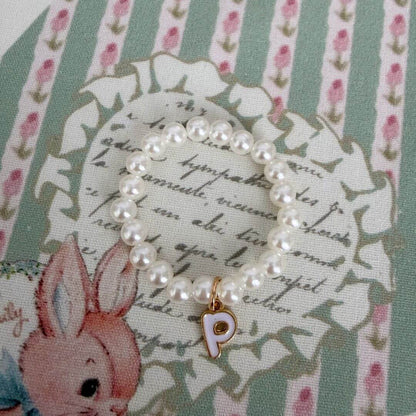 Initial Pearl Necklace with faux pearls and gold letter charm on a floral background.