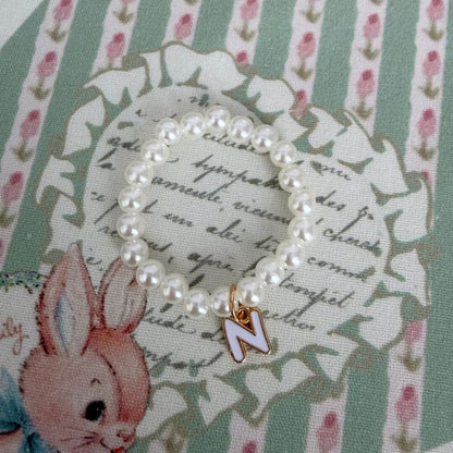 Initial Pearl Necklace with faux pearls and a delicate 'N' charm on a floral patterned background.