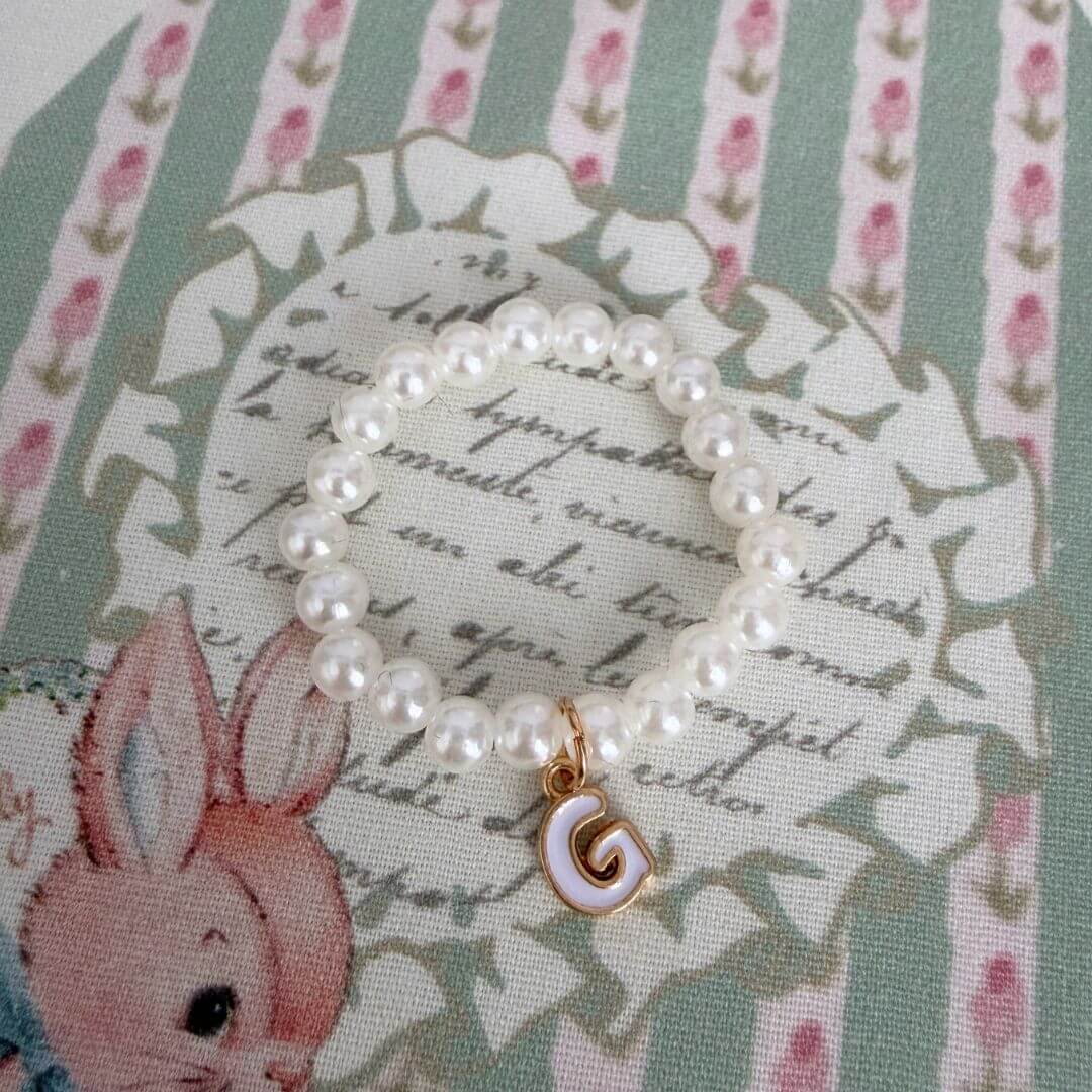 Initial Pearl Necklace with faux pearls and a gold letter G charm on vintage floral fabric background.