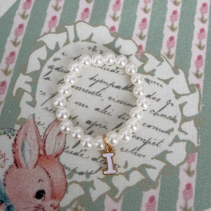 Initial Pearl Necklace with faux pearls and delicate letter charm on vintage floral backdrop.