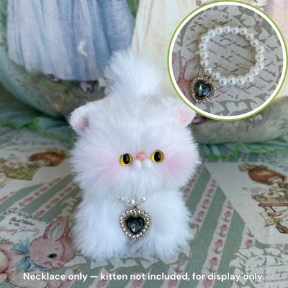 Cute fluffy cat figurine wearing an Elegant Heart Necklace with a pearl-style chain, displayed in a charming setting.