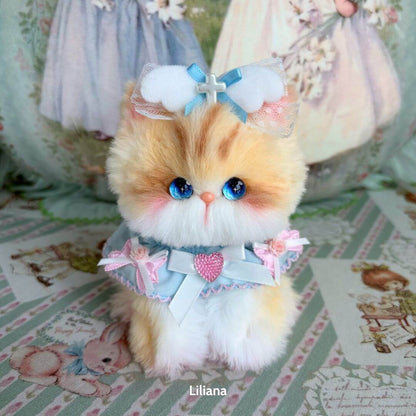 Adorable fluffy kitten from the Enchanted Big Paws Collection, dressed in a pastel outfit with a bow and glittery heart.