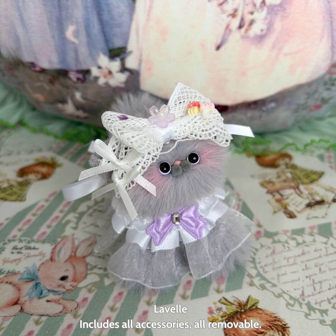 Adorable fluffy kitten from the Petals & Whispers Collection, dressed in a pastel dress and lace bow, perfect collectible decor.