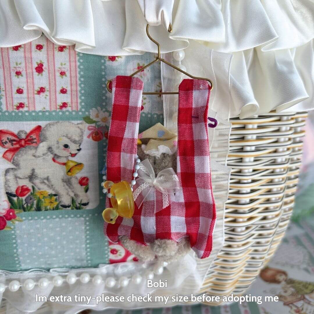 Cute handmade kitten in red gingham outfit, hanging from a miniature hanger. Little Hanger Pals collectible decor.