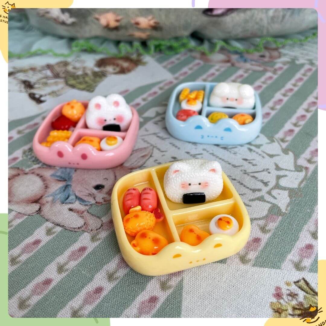 Mini Cat Bento Box featuring handmade kitten figurines in pastel pink, blue, and yellow trays with cute food items.