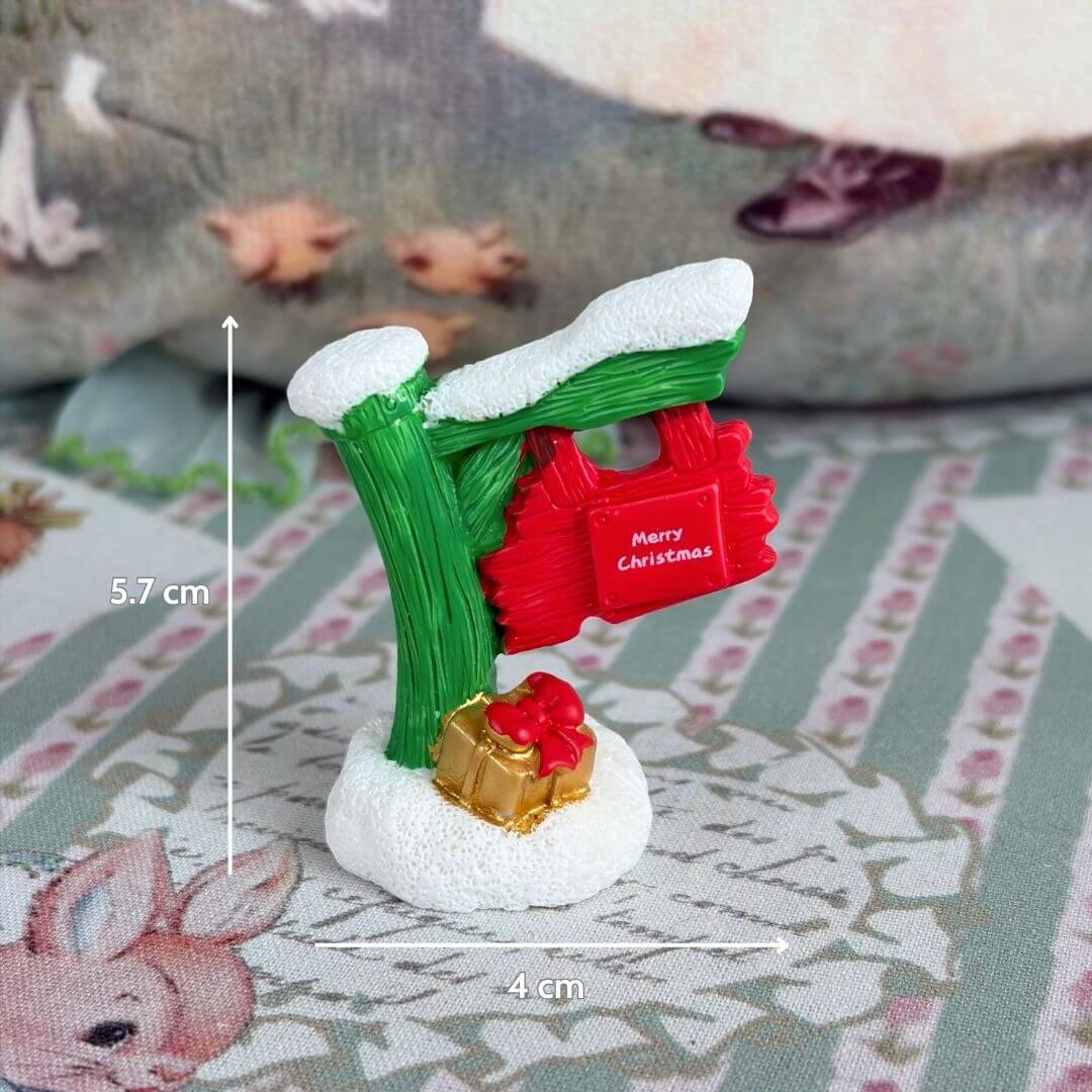 Miniature Christmas Accessories featuring a colorful sign with 'Merry Christmas', a tiny gift, and snow accents. Cute festive decor.