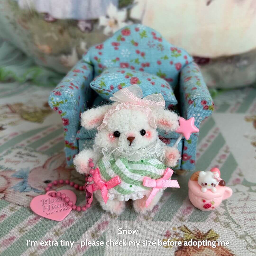 Miniature Pipe Cleaner Animals: Handmade fluffy kitten in a striped dress, holding a star, with a tiny pink teacup beside a floral chair.