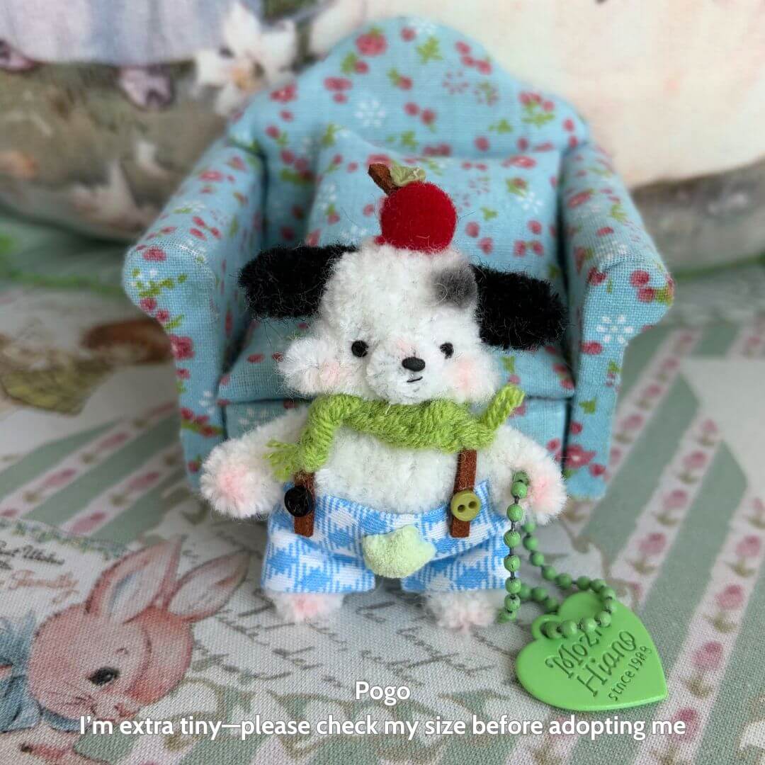 Miniature Pipe Cleaner Animals: handmade fluffy dog figurine in blue shorts with a cherry hat, posing beside a tiny floral sofa.
