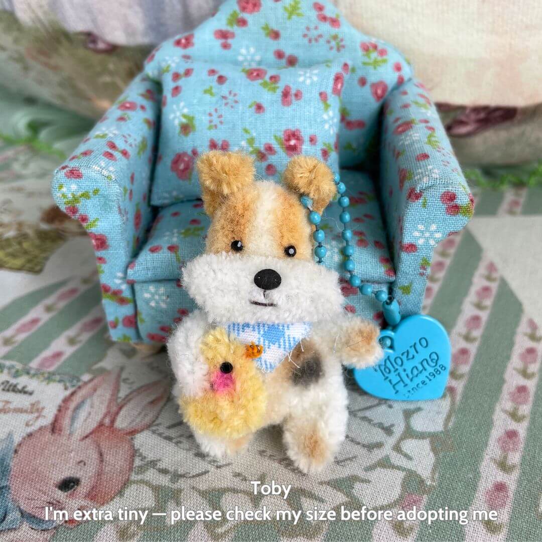 Miniature Pipe Cleaner Animals: fluffy puppy figurine in a blue floral chair, wearing a blue bandana and holding a yellow chick plush.