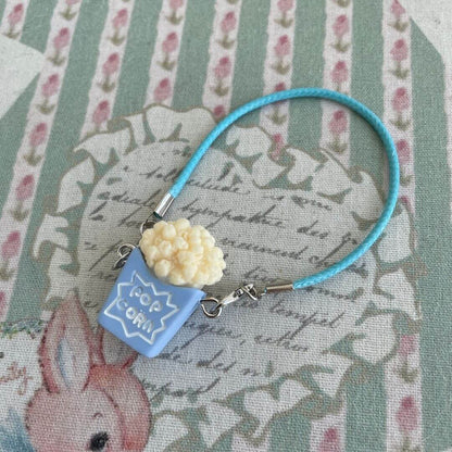 Mini Popcorn Crossbody Bag on floral background, ideal for handmade plush toy kittens and small dolls as a cute decoration or accessory.
