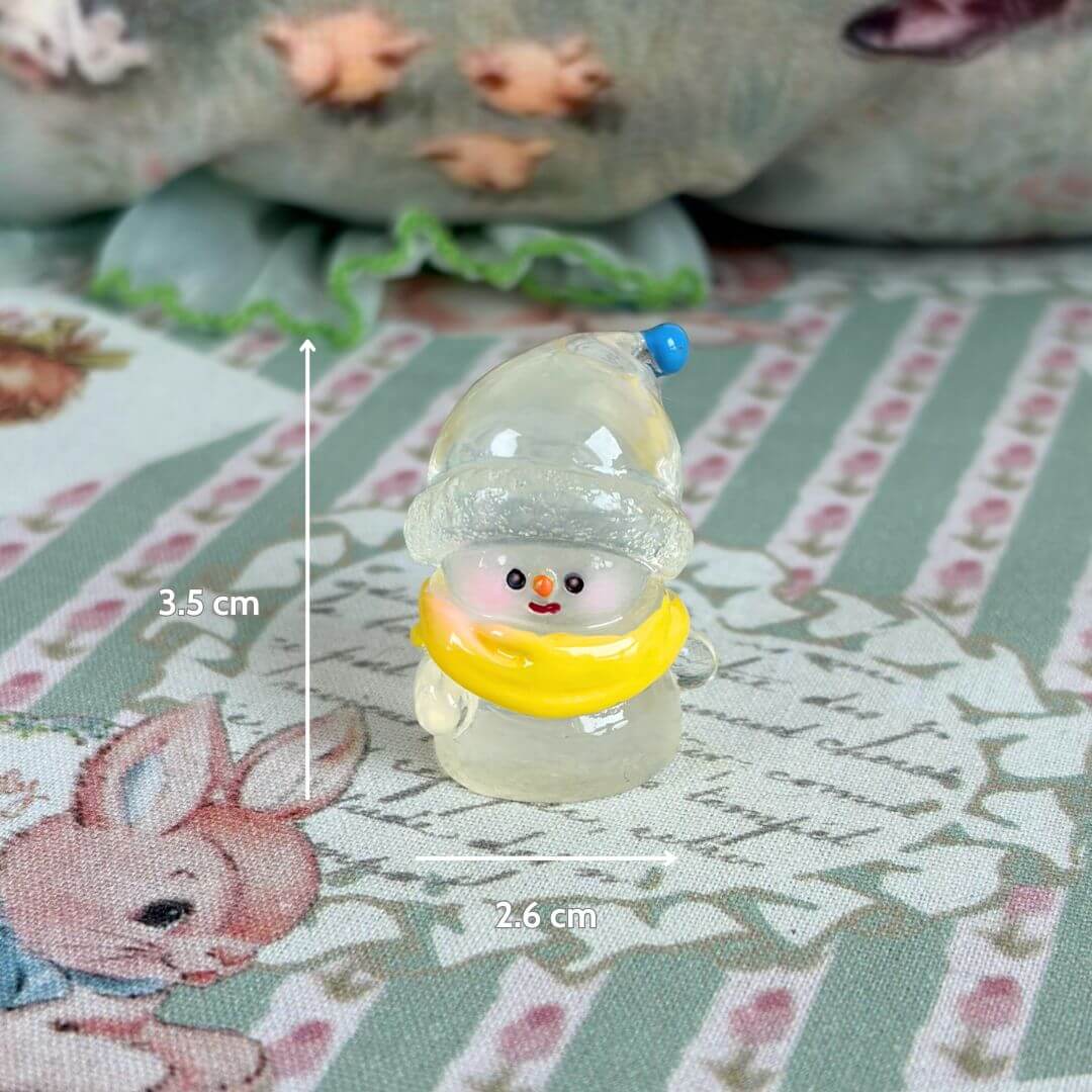Miniature Christmas Accessories featuring a handmade snowman figurine with a yellow scarf, measuring 3.5 cm, placed on a patterned surface.