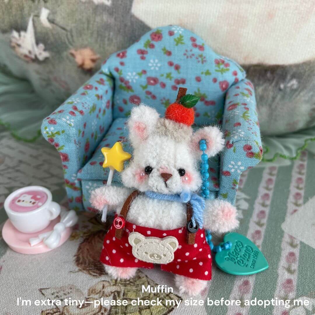 Handmade miniature plush kitten with apple hat and star wand in a blue floral chair, featuring tiny teacup and adoption note.