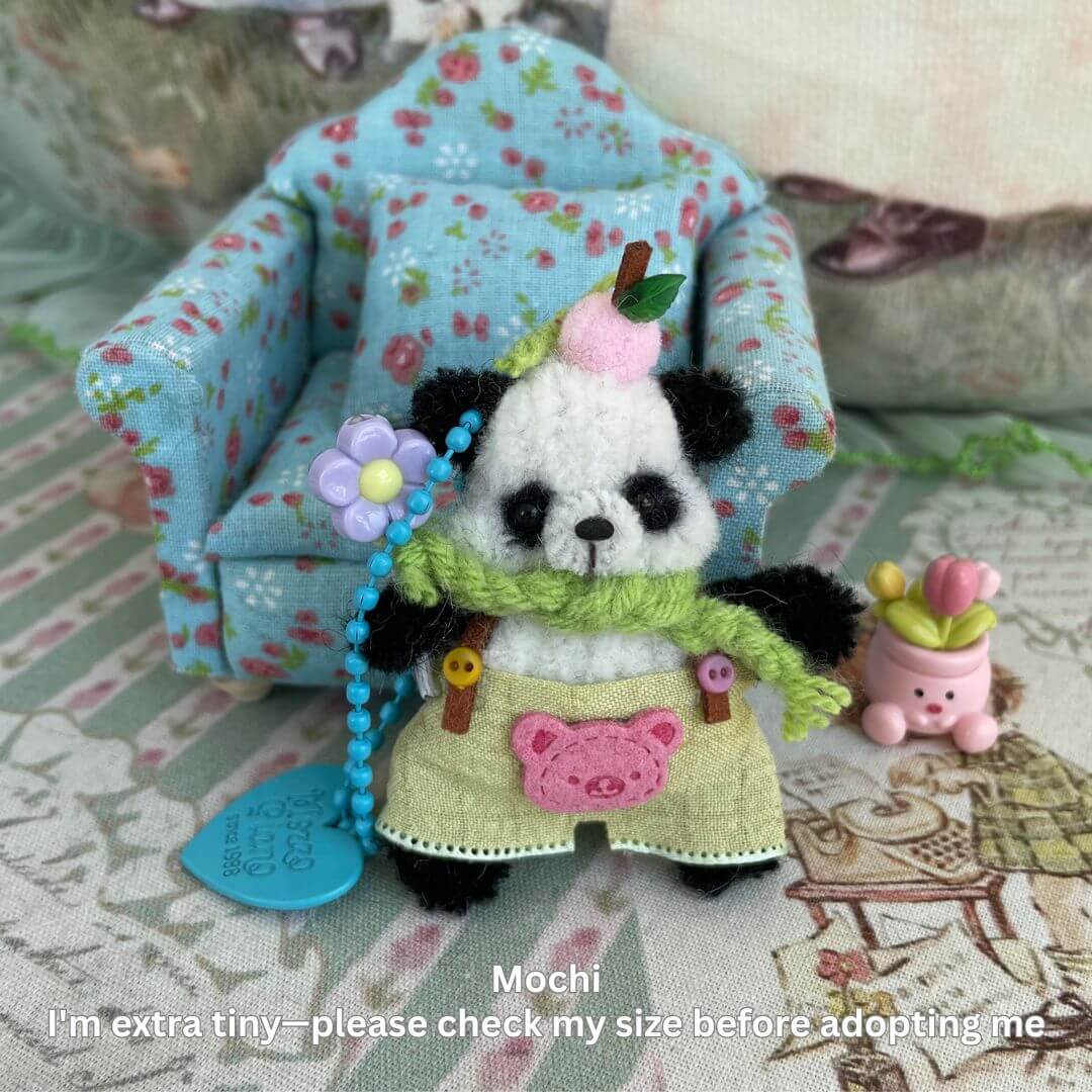 Miniature pipe cleaner panda with flower apron, keychain accessory. Handmade plush toy for decor or use as bag charm.