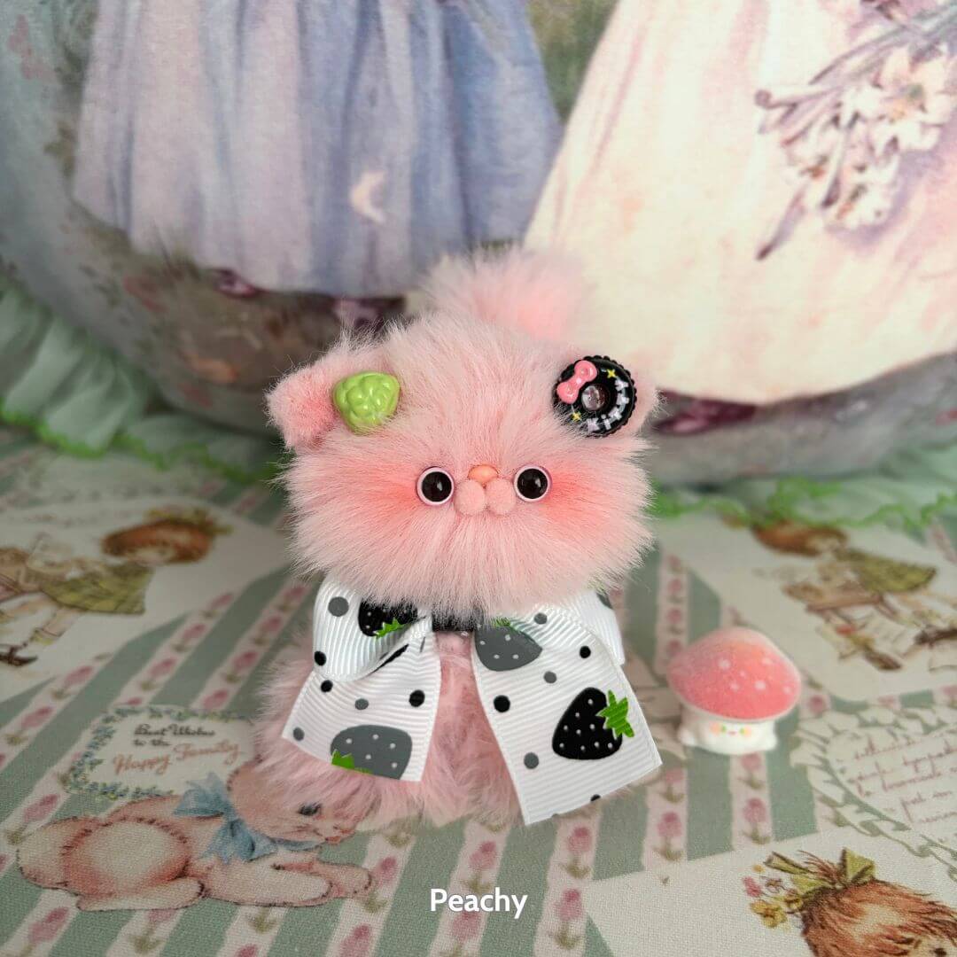 Fruity Kitten Collection: cute pink handmade kitten with black and white bow, fruity accessories, sitting on pastel patterned background.
