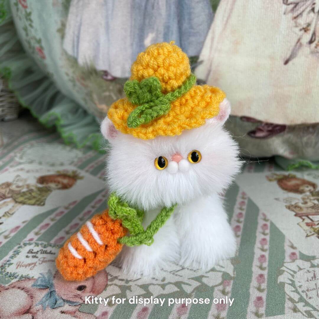 Handmade plush kitten wearing a yellow froggy hat and carrot sling, from Snuggle Bits collection. Perfect for decorating your fluffy friend.