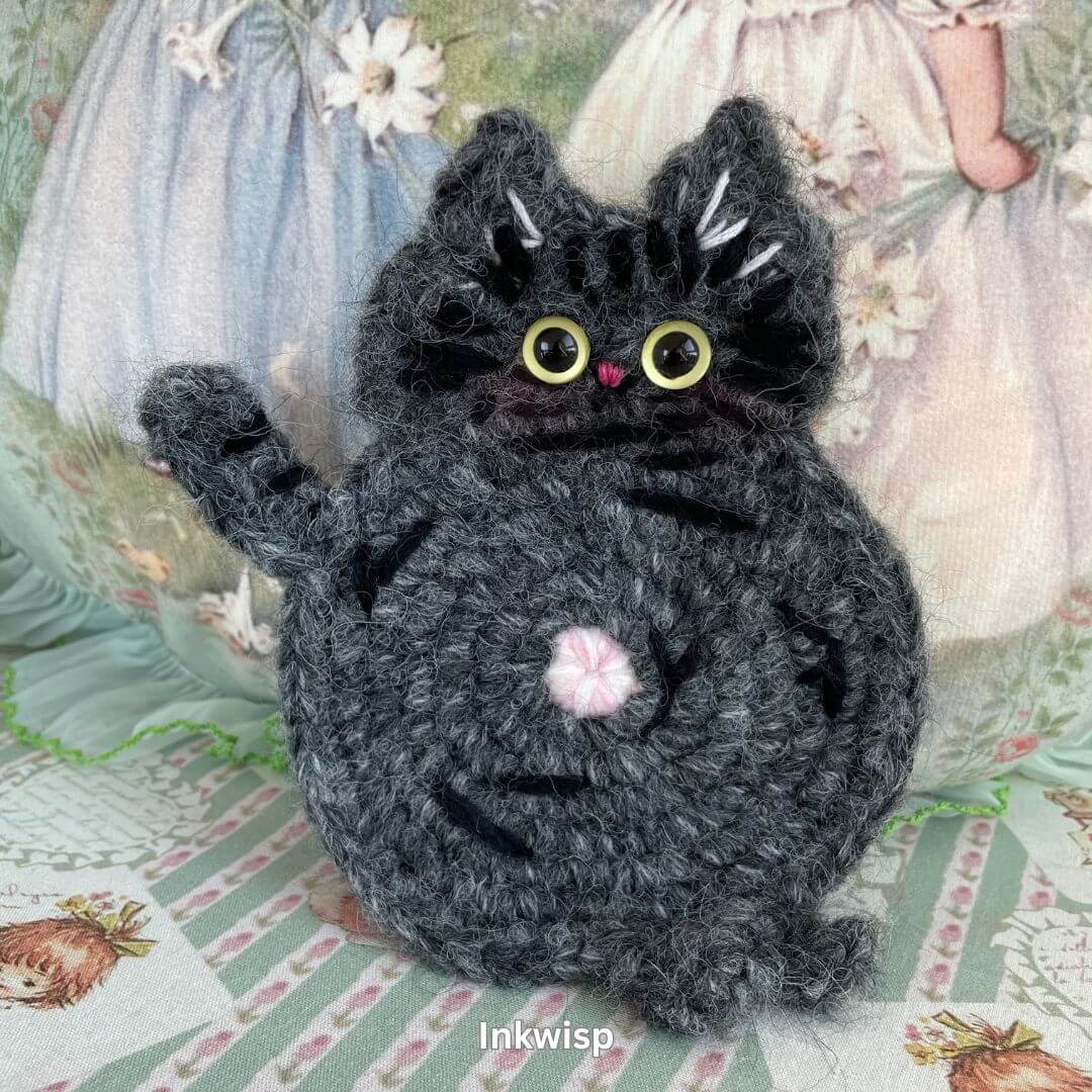 Handmade black cat coaster, crafted with yarn, adding feline charm to home decor. Perfect accessory for displaying plush toys.