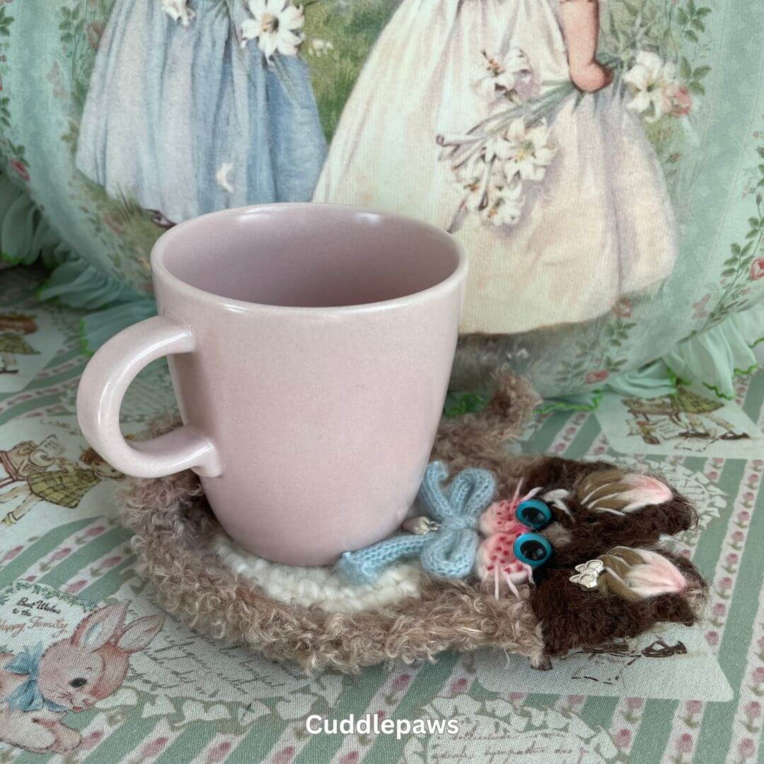 Handmade cat-themed coaster with pink mug, featuring plush kitten design by SnugglePaws. Adds feline charm to any decor.
