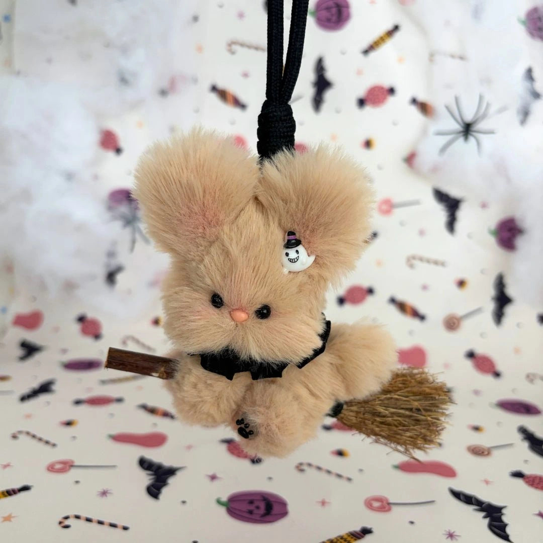 Biscuit-brown long-eared friend riding a broom with a little ghost charm.